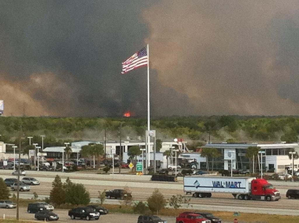 Smoke fills the sky above Bush Park Wednesday as traffic passes by on Interstate 10. Firefighters from kKaty and West Houston were called in to contain the blaze that burned over a 1500 acres. Smaller versions of the fire flared up again Thursday and Friday.