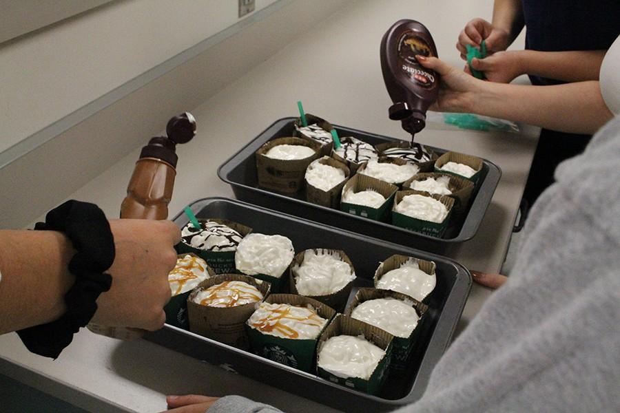 Students drizzle chocolate and caramel on top of their Starbucks inspired cupcakes as a finishing touch. 