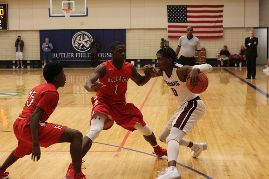 Senior Jay Jay Chandler defends the ball from two Bellaire players as he makes his way across the court to score.