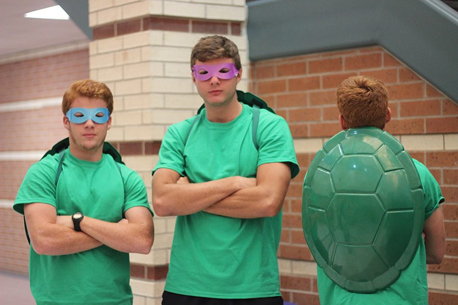 Two ninja turtles cross their arms as a third shows off his shell.  Some groups of friends dressed up as the same character.