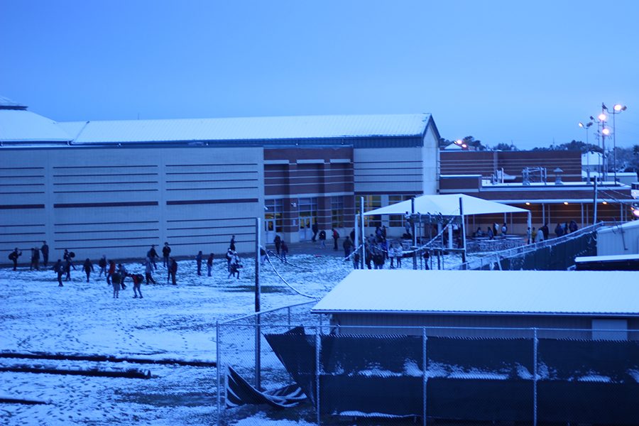 Students gather to play in the snow behind the main commons as the sun rises.